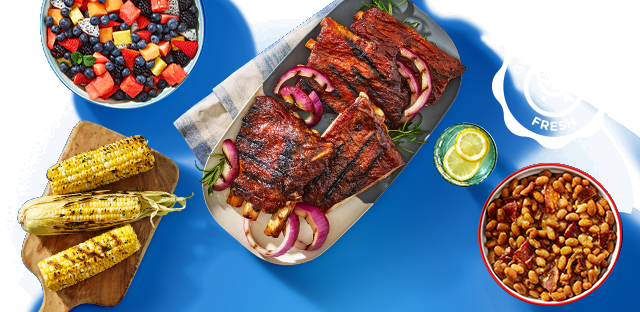 Grilled ribs, corn, beans, and mixed fruit display. Grilled ribs, corn, beans, and mixed fruit display.