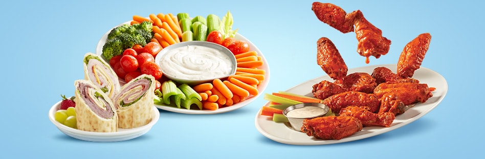 Wraps, vegetable plate, and plate of buffalo wings.