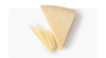 Parmesan cheese wedge and slices on a white surface