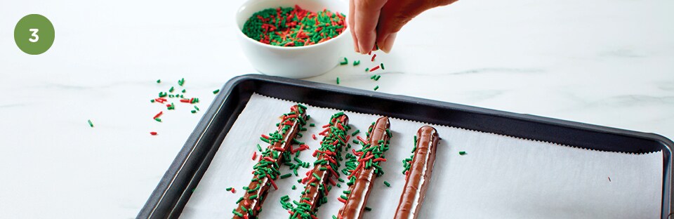 hand dropping sprinkles on pretzels