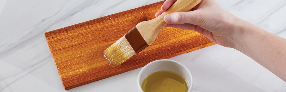 Brushing olive oil on wood plank