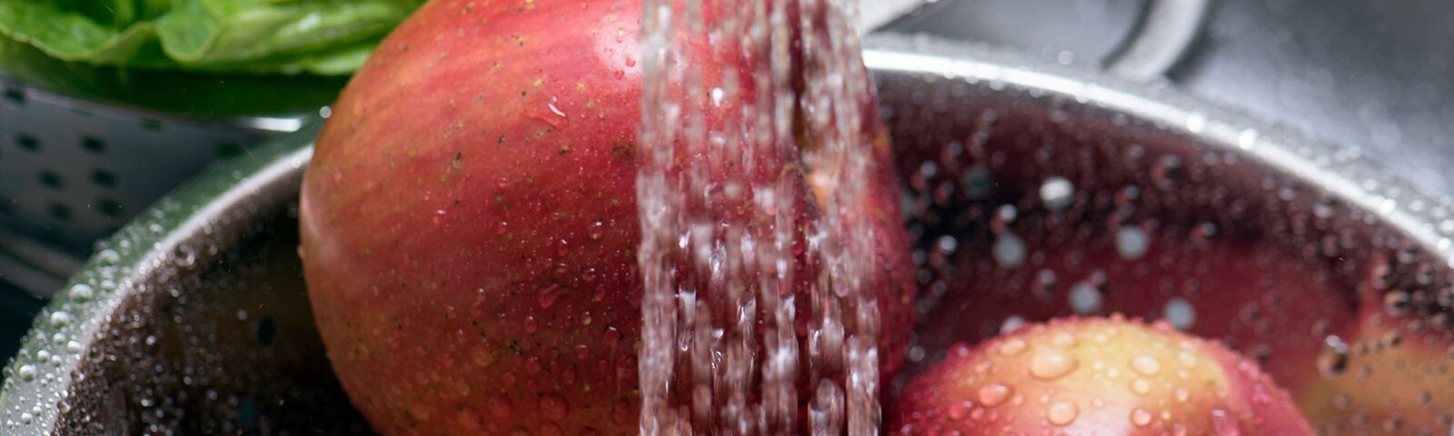 Washing red apples in a metal bowl with running water Washing red apples in a metal bowl with running water