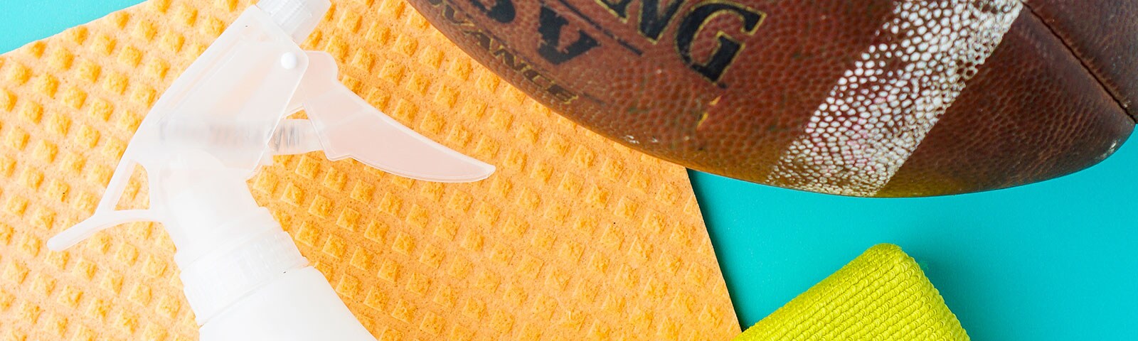 A dish towel, a football, and a spray bottle sitting on a blue background A dish towel, a football, and a spray bottle sitting on a blue background