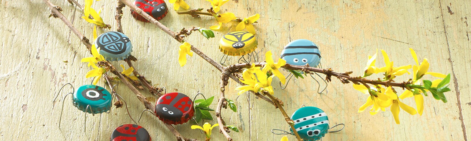 Lady bug and spider painted bottle caps attached to a thin tree branch