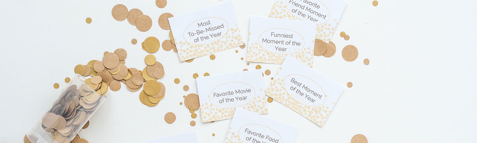 White cards with New Year's prompts printed on them surrounded by large gold confetti White cards with New Year's prompts printed on them surrounded by large gold confetti