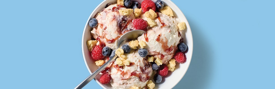Vanilla ice cream sundae with mixed berry preserves, fresh berries and crushed shortbread cookies