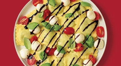 Cooked ravioli with tomatoes, mozzarella and basil and balsamic glaze or dressing.